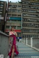 A woman in a pink dress standing on a bridge.